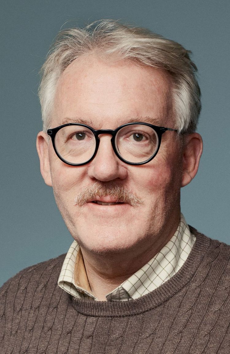 Mann med runde briller ser inn i kamera